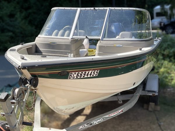 A 2006 Crestliner 1650 Sport Angler (Reg. BC6694455) sits on a trailer, featuring a windshield, seats, and a white body with green and brown stripes; trees and greenery are visible in the background.