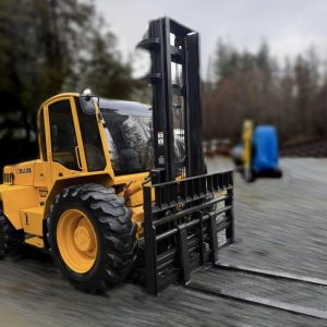 A 2015 Sellick S80 4x4 forklift, 8000lb capacity and yellow in color, with large tires, is parked on gravel near trees and some blurred background objects on a cloudy day.