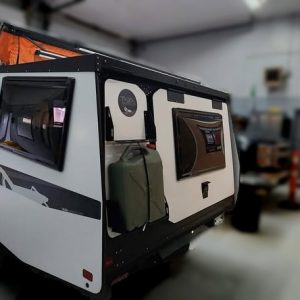 White 2021 Taxa Mantis travel trailer with an orange pop-up roof and an olive green jerrycan mounted to the back.